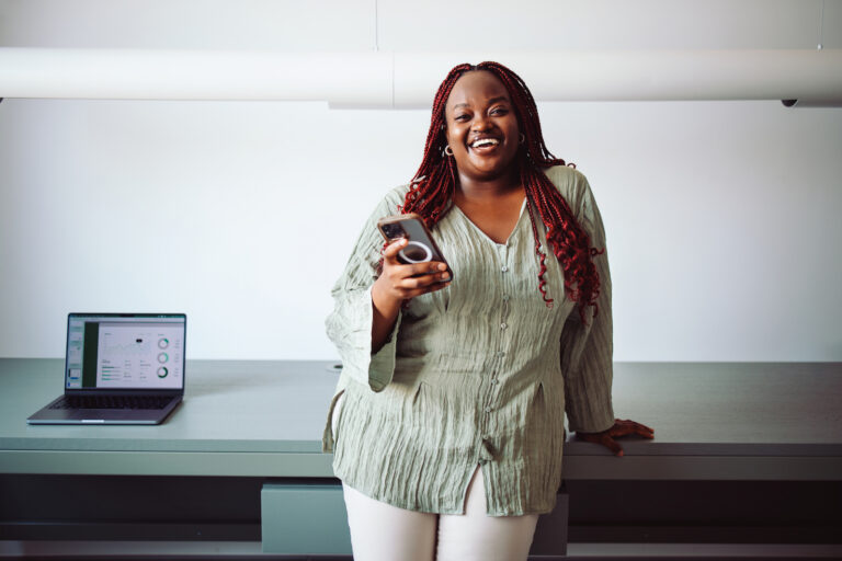 Woman Holding Smartphone Beside Laptop
